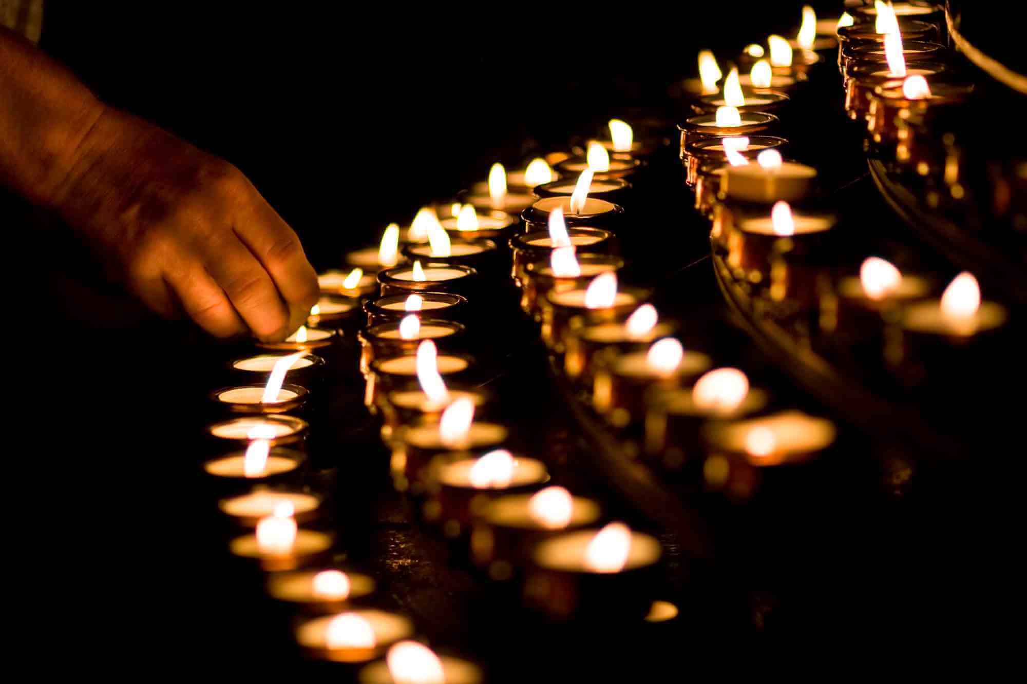 Christian lighting candles in a church to commemorate the death of a loved one